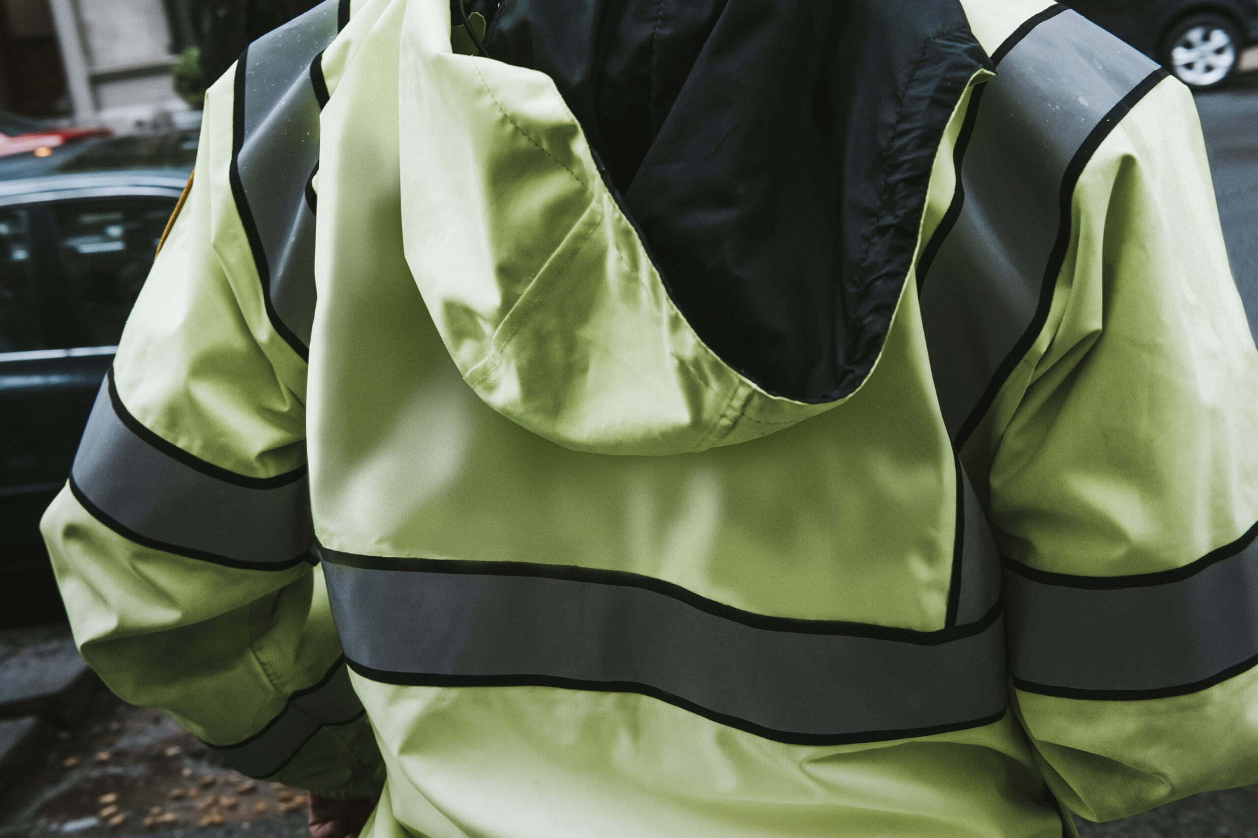 Rearview of a man in a high visibility jacket by the street